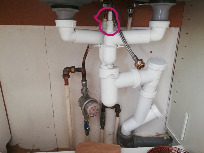 Under-sink plumbing with parts highlighted in pink, indicating areas of interest or concern.