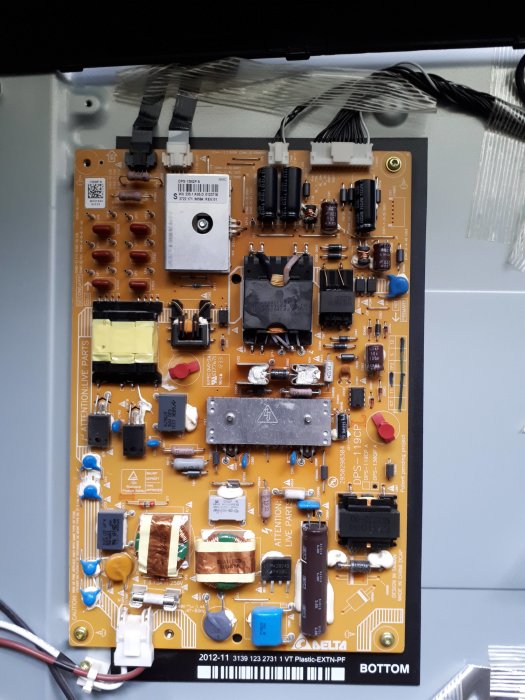 Ett uppskruvat power supply-kort med elektroniska komponenter, lösa skruvar synliga.