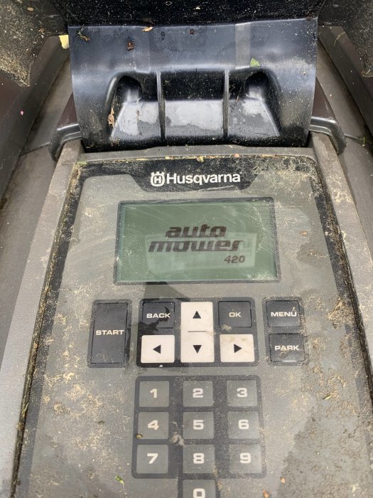 Skitig display och knappsats på en Husqvarna Automower 420, visas fastnat på startskärmen.