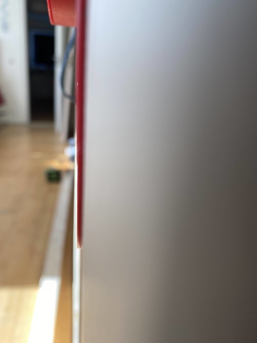 Mätsticka hållen mot en vit vägg för att visa avståndet till en regel i byggprojekt.