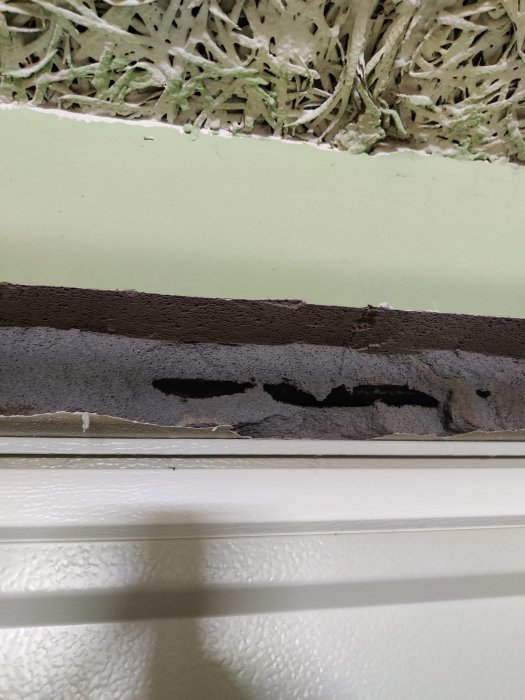 Lättbetongvägg med synligt kapningsförsök ovanför en garageport, exponerar ett horisontellt armeringsjärn.