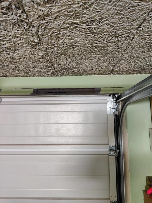 Armeringsjärn i lättbetong ovanför en garageport, med delvis kapad betong för höjdjustering.