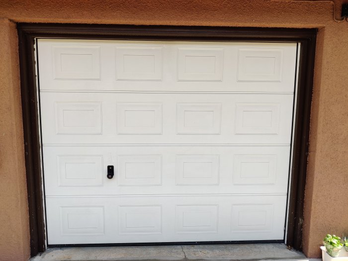 Stängd vit takskjutport monterad i husfasad av lättbetong.