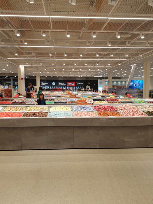 Lösgodisavdelning med olika sorter i en nästan tom butik.