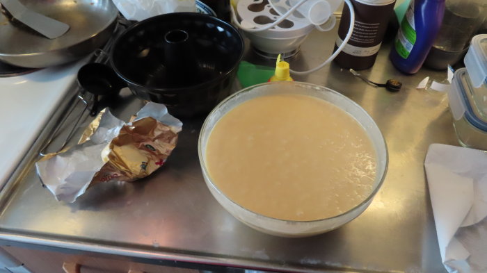 Citronsockerkakssmet redo i en rund glasform på ett köksbord med bakredskap och ingredienser.
