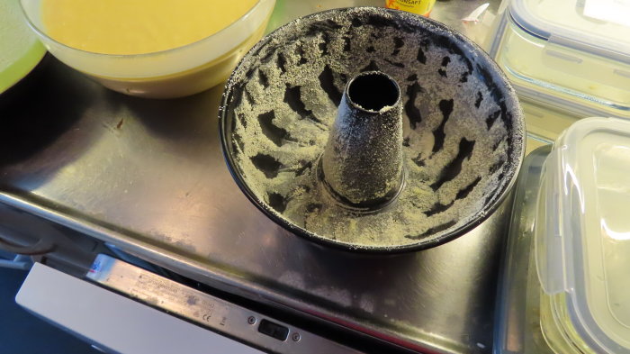 Tom bakform för sockerkaka med rester av smör och mjöl på en köksbänk.