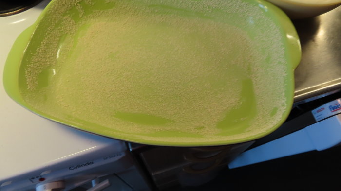 Grön bakform med rester av mjöl, förberedd för att bakas i.