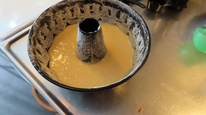 Sockerkakssmet i en smord och bröad sockerkaksform på ett köksbord.