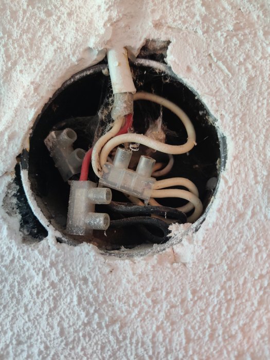 Eluttagets insida med synliga äldre elektriska ledningar och kopplingar i isolerat rum från en renovering.