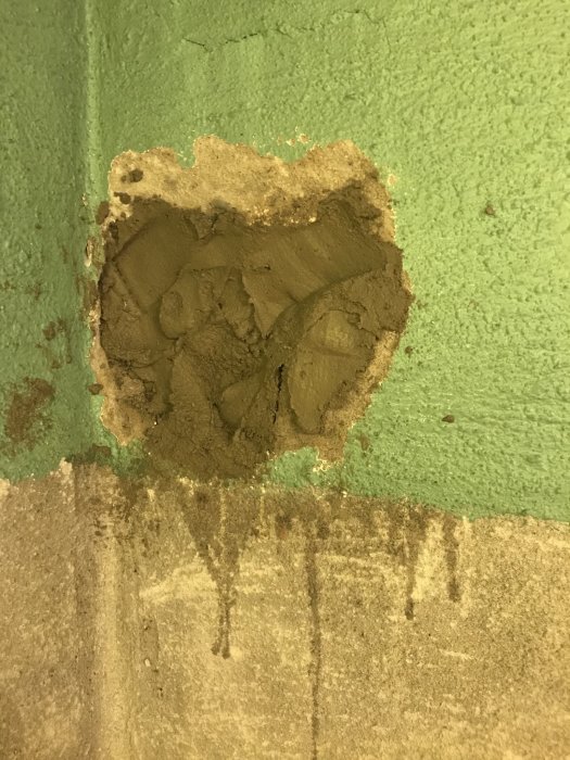 Nyapplicerat B-bruk på en vägg med grönt ovanför och oputsat område nedanför.