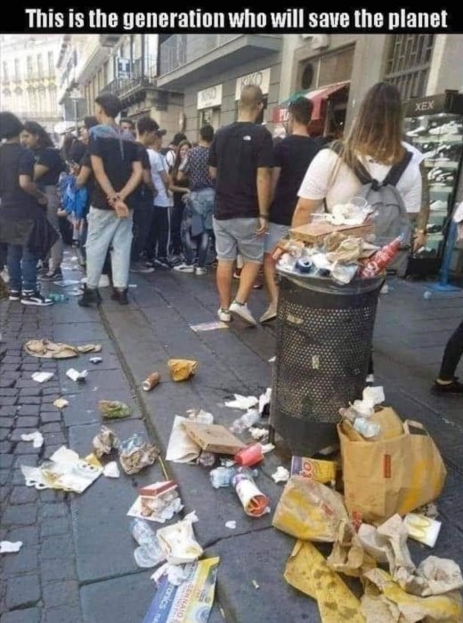 Överfull soptunna med skräp omkring på gatan och folk i bakgrunden.