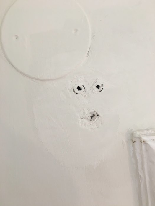 Vägg med ojämnt spackel och hål för gardinstångshållare, redo för montering.