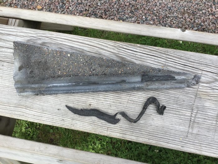 Snedsågad takpanna med misslyckad limning på ett träbänk.