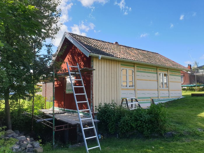 Renoverat hus med nytt fönster och nymålad fasad med isoleringsmaterial och stege.