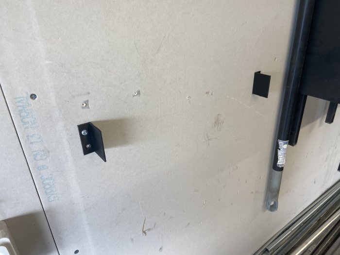 Väggmonterade fästen för verktygsförvaring på en OSB-skiva med synliga skruvar.
