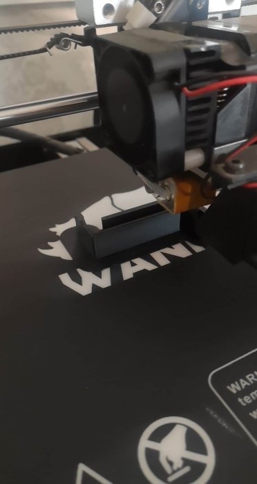 3D-skrivare som skapar ett väggfäste med en logotyp på tryckplattan.