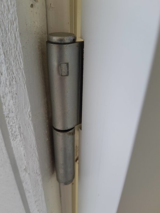 Närbild på ett altandörrsgångjärn utan synliga justeringsskruvar.