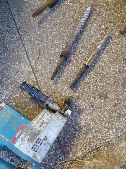 Gammal borrhammare och tre borr med okända fästen på betonggolv.