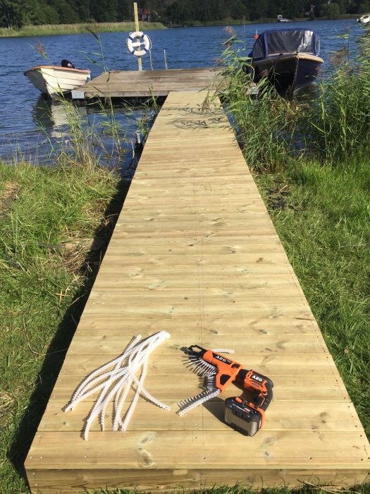 Nybyggd trallväg till bryggan med en AEG skruvautomat och vita bojlinor på det solbelysta träet.