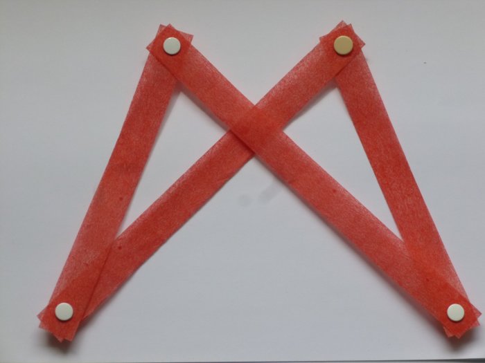 Enkel geometrisk modell med röda band som korsar varandra fastsatta med vita knappnålar.