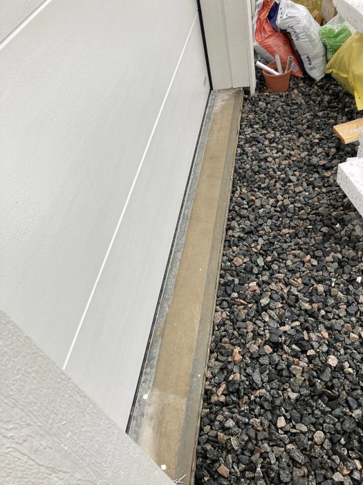 Bild på garagegrunden där en framtida takport skall installeras, intill grus och byggmaterial.