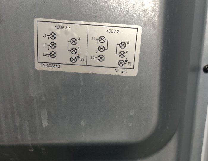 Etikett med elektriska anslutningsscheman för 400V 3- och 2-fas koppling på en maskin.