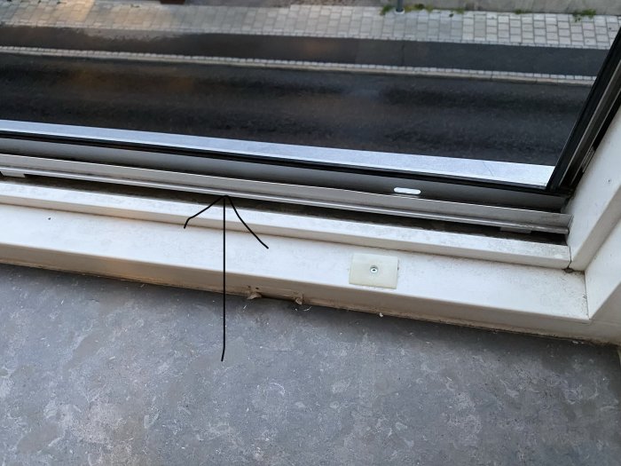Böjd skena i en öppen fönsterkonstruktion som hindrar stängning, sett inifrån ett rum.