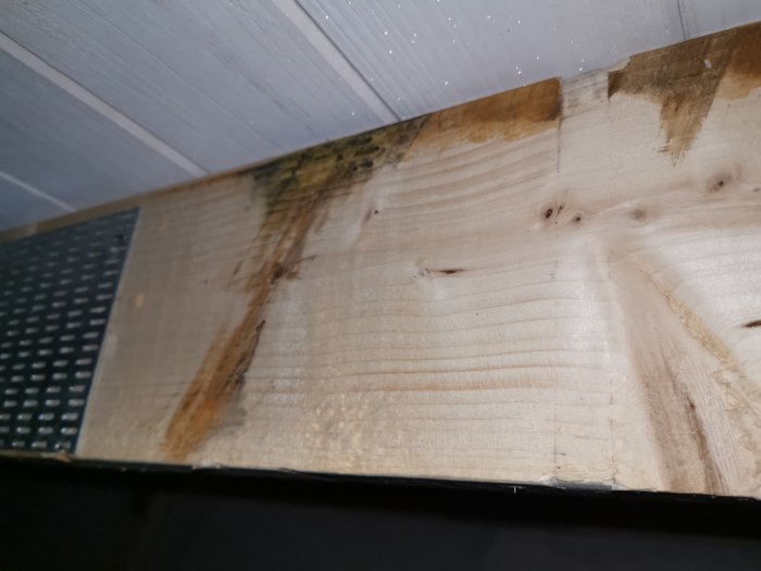 Träbjälkar på vind med missfärgningar som kan tyda på möjliga fuktskador, trots att träet känns torrt.