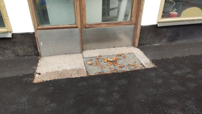 Fastighetens entré med nyhöjd trottoar och gallersten i nivå med omgivande asfalt.