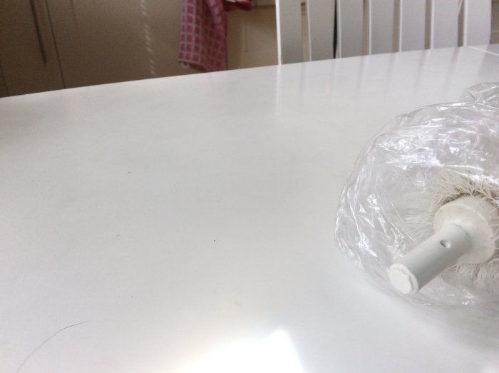 Litet skaft på föremål för montering, ligger på vit yta med plastförpackning.