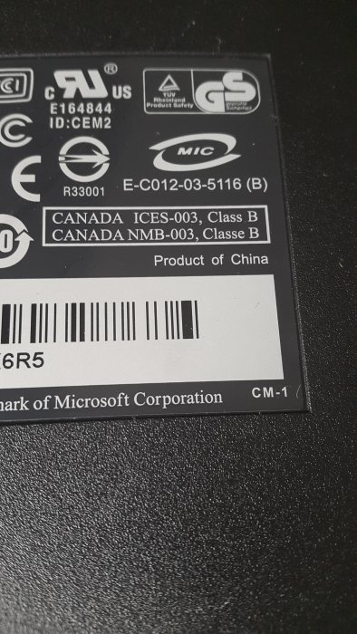 Bild av etiketten på baksidan av ett Microsoft-tangentbord med olika certifieringsmärken och streckkod.