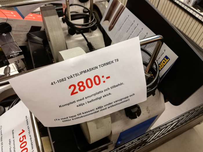 Prislapp på Tormek T8 vattenslipmaskin för 2800 kronor på hylla, del av T4 modell syns till vänster.