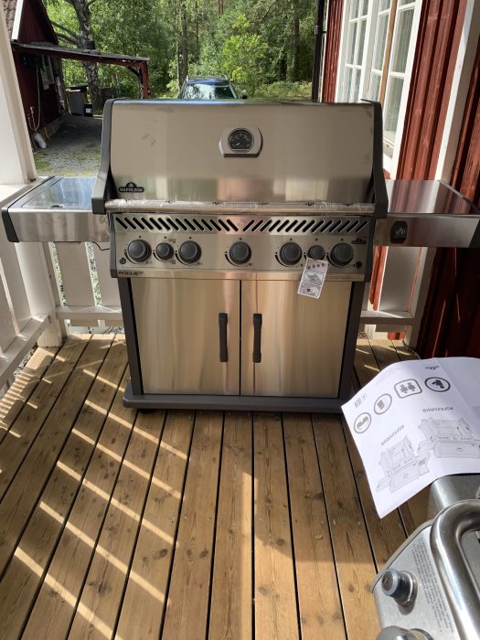 En ny gasolgrill av nordamerikanskt märke på en träveranda med instruktionsmanual och stekhäll synlig.