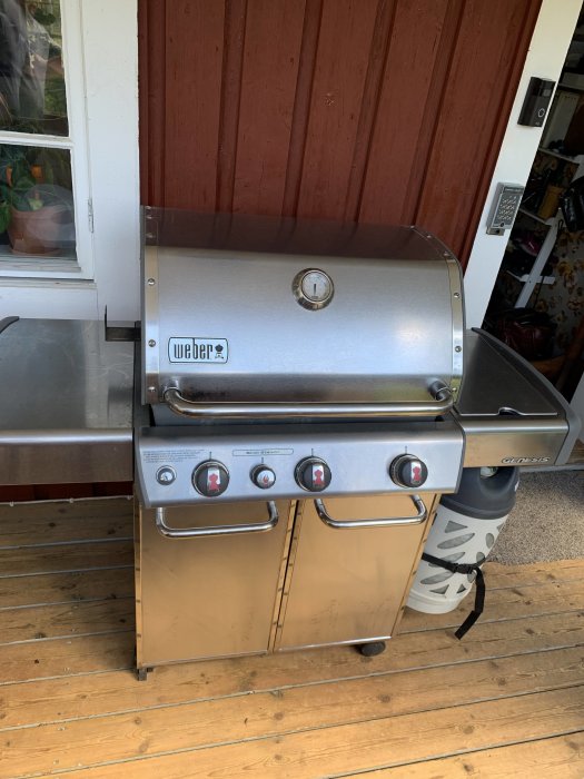 Weber Genesis gasolgrill på en träveranda, rostfritt stålutförande med tre brännare och temperaturmätare.