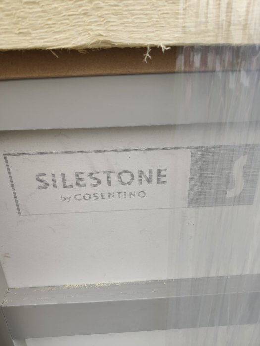 Logotypen "SILESTONE by COSENTINO" tryckt på skyddsplasten av en levererad bänkskiva.