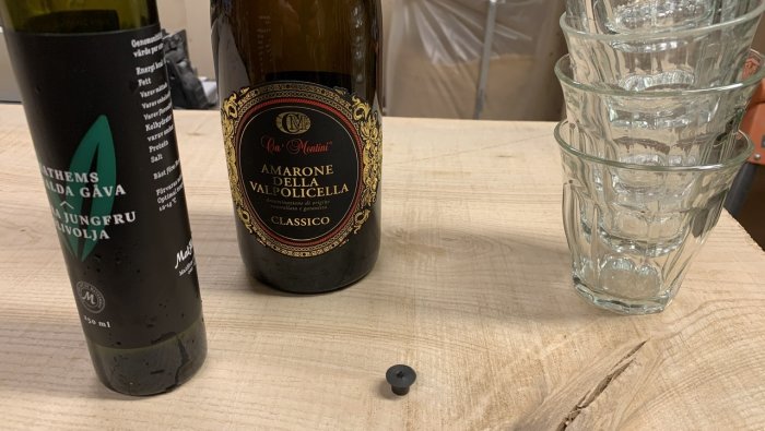 Två flaskor och staplade dricksglas på en behandlad träyta för att testa ytskiktets tålighet.