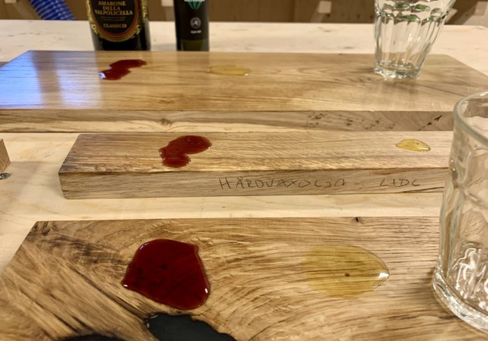 Ekplankor behandlade med olika skyddsoljor och lacker testade med vinfärgning, oljefläck och avtryck av vått glas.