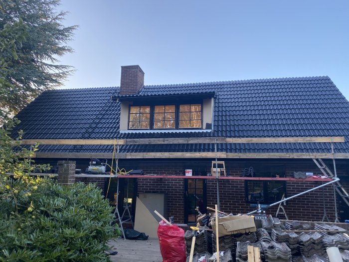 Nyrenoverad södra sida av tak med svarta pannor och välkapade gavelpannor på en villa.