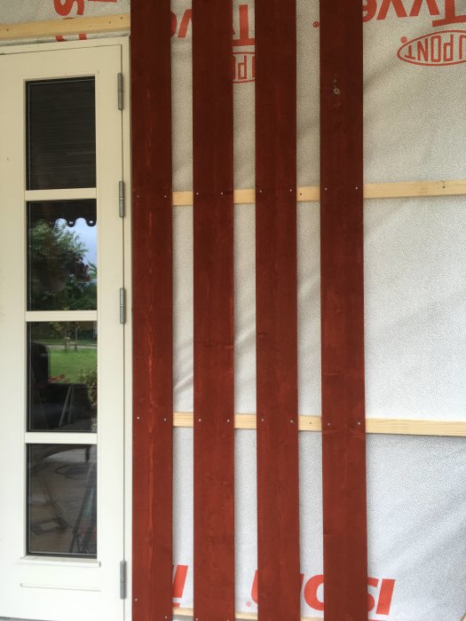 Renoveringsarbete med rödmålad panel som monteras på vindskydd för ökad luftspalt och förbättrad ventilation.