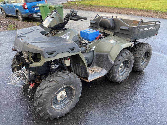 Reparerad 6x6 terränggående fordon, synliga svetsar och däck, parkerad utomhus.