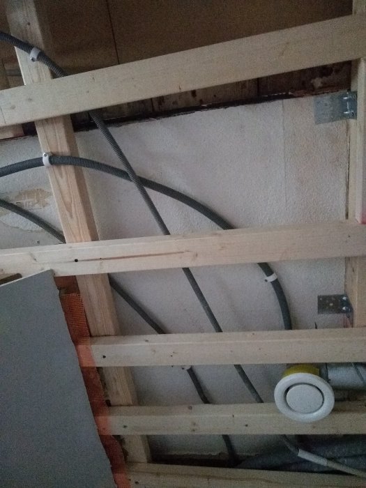 Byggkonstruktion med reglar, isolering och elinstallationer synligt under arbete.