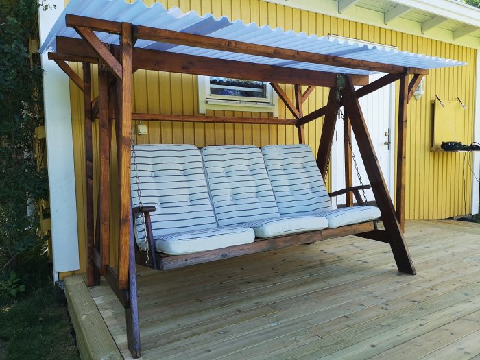 Hammock med ombyggt tak av plast och nya träreglar för bättre lutning, invid ett gult hus.