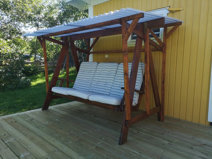 Hammock med nytt permanent plasttak och träreglar på en altan.