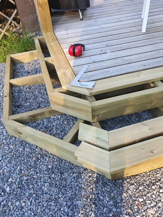 Trätrappa under konstruktion med en felplacerad bräda och mätverktyg markerar problemområdet.