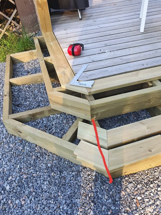 Trätrappa under konstruktion med markerad kapning på frisbrädan och verktyg på däck.