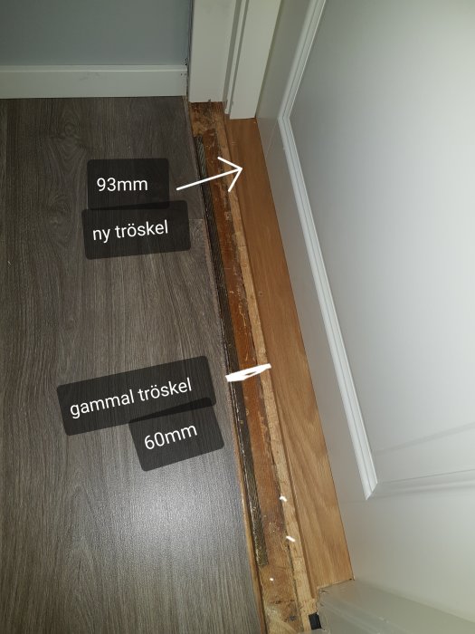 Renovering av dörrtröskel där ny 93mm tröskel jämförs med äldre 160mm tröskel på laminatgolv.