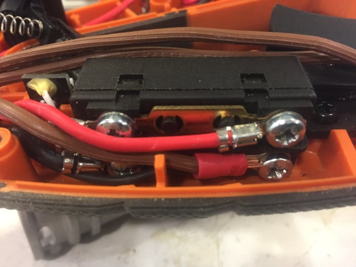 Närbild av öppnad sågens brytare fixerad med ett buntband och modifikationer på kablar.