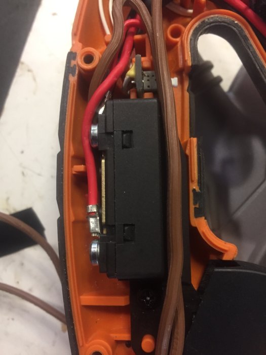 Inre delen av en såg med synlig brytare, kabel och anslutningsplintar.