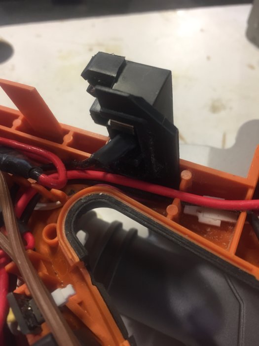 Inre av en såg visande en brytare fastsatt med buntband och synliga anslutningsplintar.