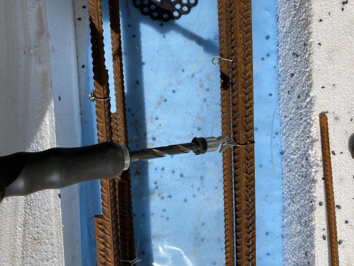 Verktyg som snurrar hemmagjorda säcktrådar runt armeringsjärn på en byggarbetsplats.